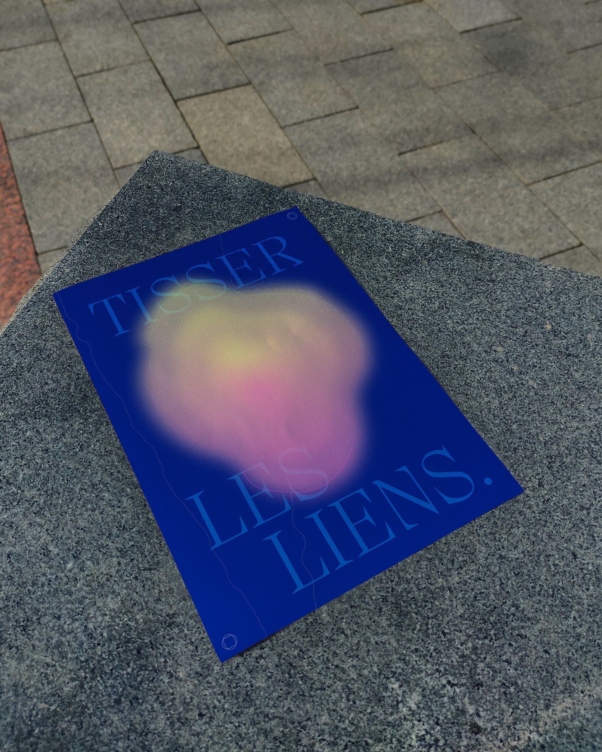 Affiche « Tisser les liens » posée sur un banc de granit